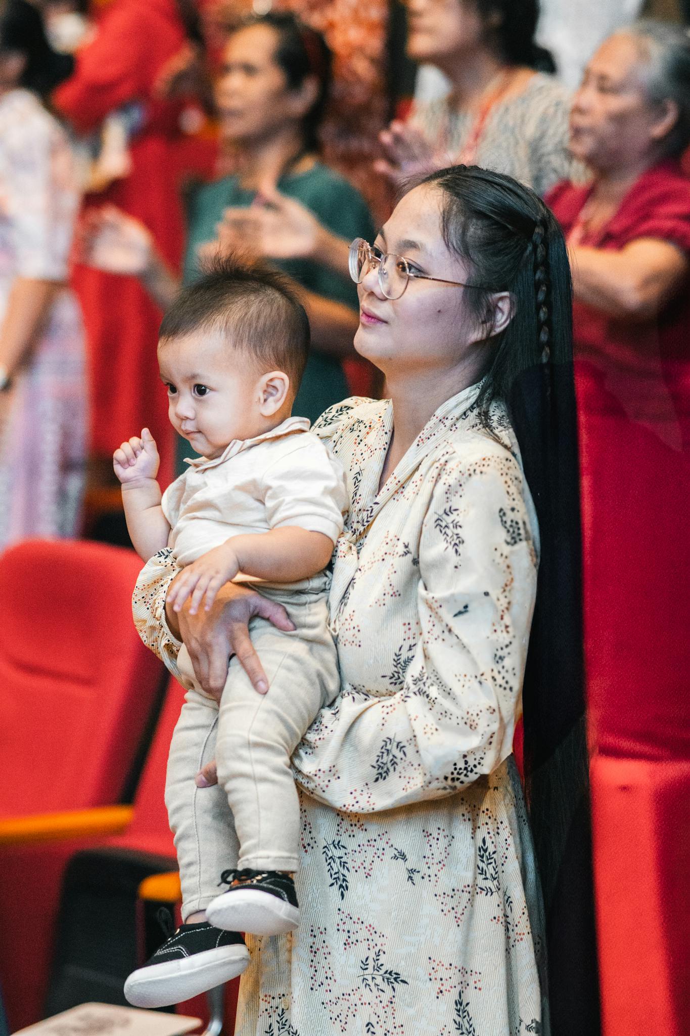 A mother holds her child during a lively church service filled with worshippers.